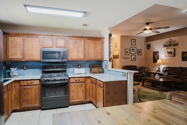 kitchen with stainless steel microwave, black range with gas stovetop, visible vents, open floor plan, and a peninsula