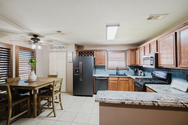 kitchen featuring visible vents, a sink, backsplash, stainless steel appliances, and a peninsula