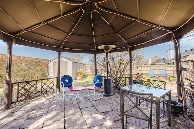 view of patio with a storage unit, outdoor dining area, an outbuilding, and a fenced backyard