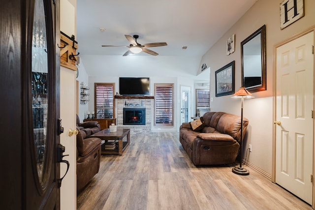 living area featuring visible vents, a ceiling fan, light wood-style floors, a stone fireplace, and lofted ceiling