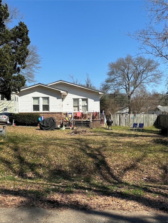 exterior space featuring a yard, fence, brick siding, and a wooden deck