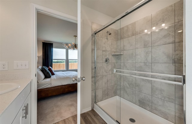 bathroom with vanity, wood finished floors, ensuite bath, a shower stall, and a chandelier