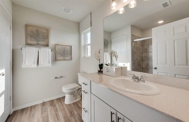 bathroom with visible vents, toilet, wood finished floors, and a shower stall