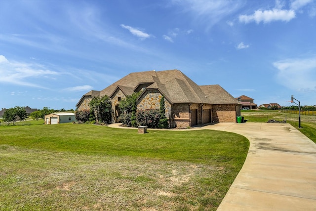 view of front of home with a front yard, brick siding, stone siding, and driveway