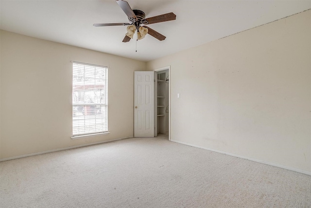 carpeted spare room featuring a ceiling fan and baseboards