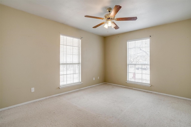 empty room featuring a wealth of natural light, baseboards, carpet, and ceiling fan