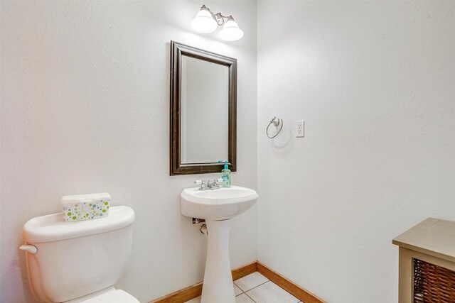 half bath with tile patterned floors, toilet, and baseboards