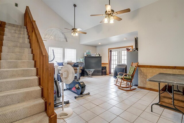 living area with visible vents, high vaulted ceiling, a ceiling fan, light tile patterned flooring, and stairs