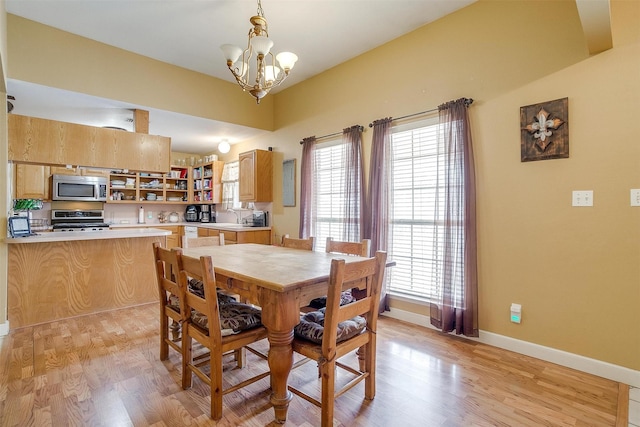 dining area featuring a wealth of natural light, light wood-type flooring, baseboards, and a notable chandelier