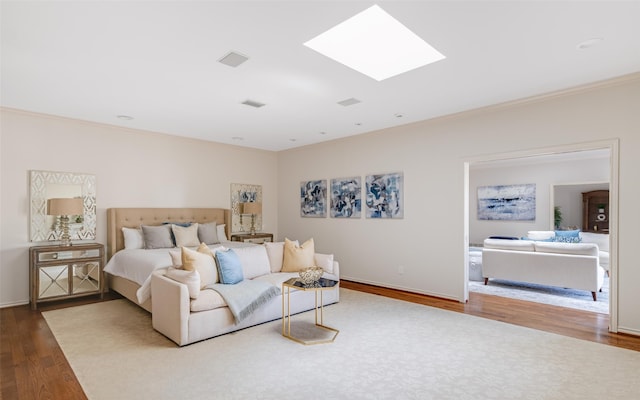 bedroom featuring a skylight, baseboards, wood finished floors, and ornamental molding