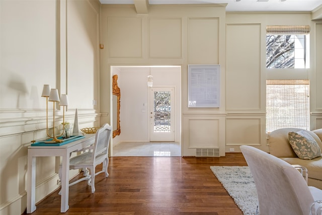 entrance foyer featuring a decorative wall, wood finished floors, and visible vents