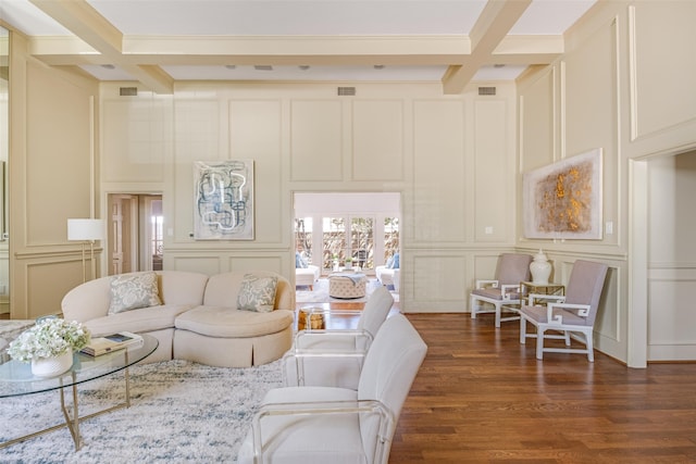 living room with beam ceiling, coffered ceiling, dark wood-style flooring, and a decorative wall