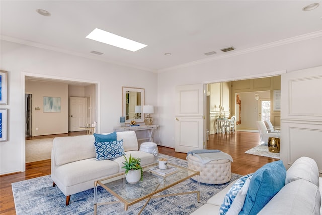 living room featuring visible vents, wood finished floors, a skylight, and crown molding