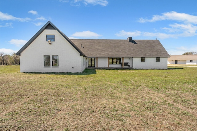 back of property with a yard and roof with shingles