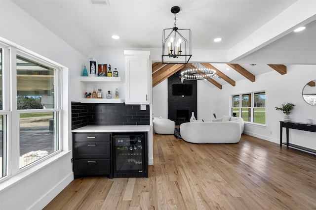 bar with beverage cooler, vaulted ceiling with beams, a dry bar, tasteful backsplash, and a chandelier