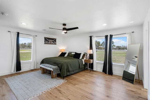 bedroom featuring visible vents, light wood-style flooring, baseboards, and ceiling fan