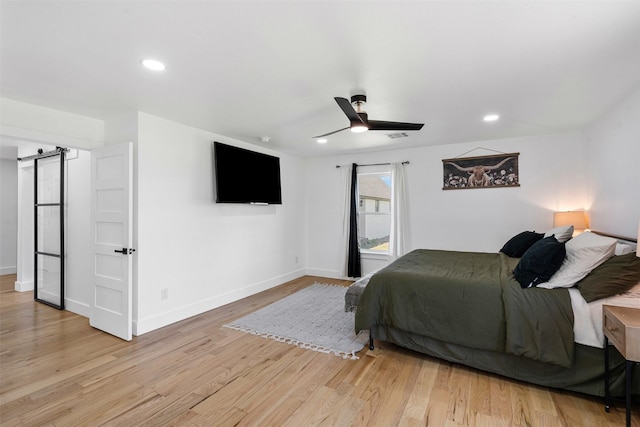 bedroom featuring recessed lighting, baseboards, a barn door, and wood finished floors