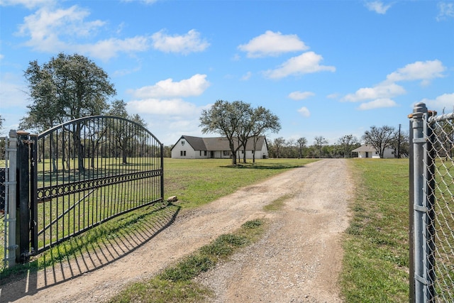 view of street featuring a gate, dirt driveway, and a gated entry