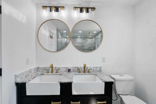 bathroom with double vanity, toilet, walk in shower, and a sink