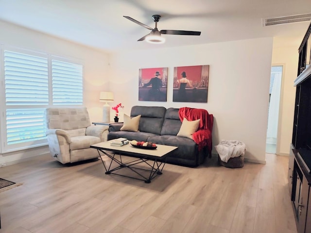 living room featuring a ceiling fan, visible vents, and light wood finished floors