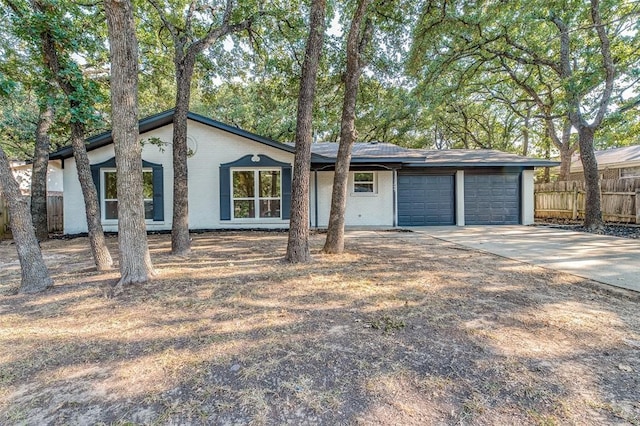 mid-century modern home featuring brick siding, concrete driveway, a garage, and fence