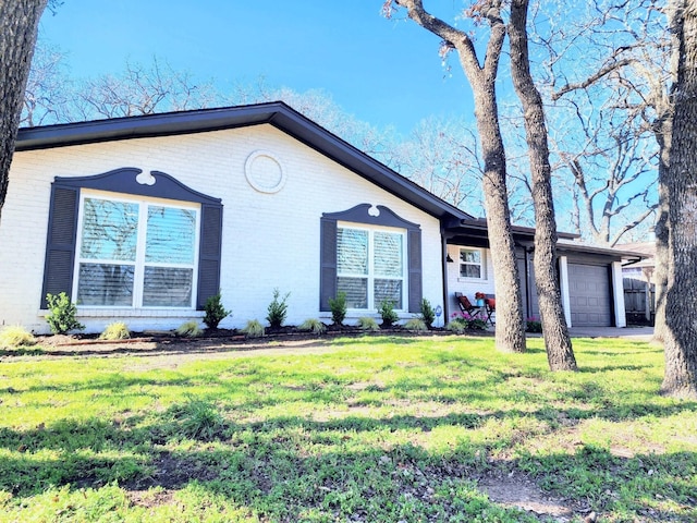 view of front of home featuring brick siding, a front lawn, and a garage