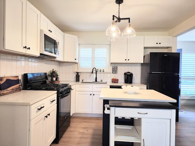 kitchen with light wood finished floors, black appliances, decorative backsplash, white cabinetry, and a sink