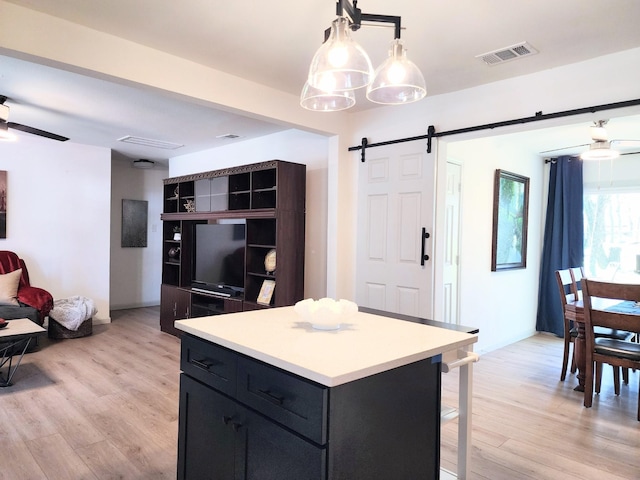 kitchen with visible vents, a barn door, light wood-style floors, and light countertops