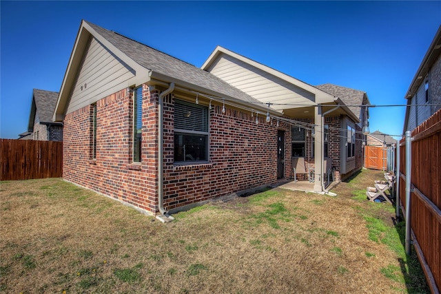 rear view of property with a lawn, brick siding, and a fenced backyard