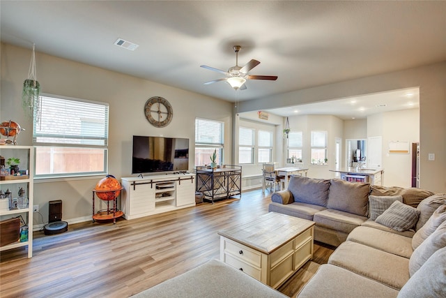 living area with ceiling fan, visible vents, baseboards, and wood finished floors