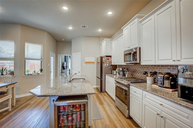 kitchen featuring visible vents, a sink, decorative backsplash, stainless steel appliances, and white cabinetry