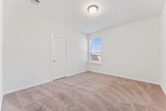 empty room featuring visible vents, baseboards, and light colored carpet