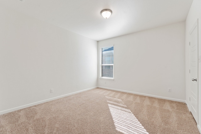 spare room featuring baseboards and light carpet