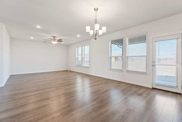 empty room with recessed lighting, baseboards, wood finished floors, and ceiling fan with notable chandelier