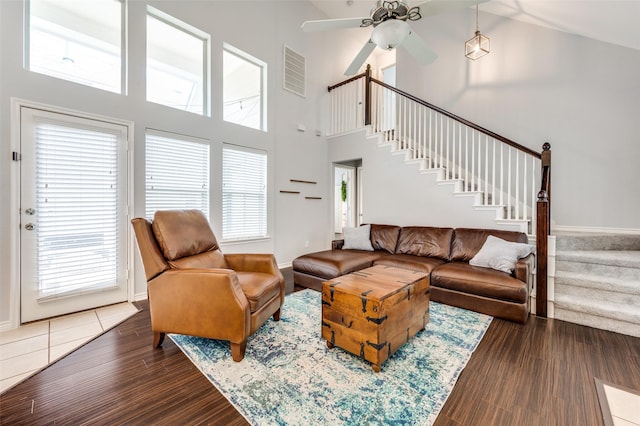 living area with visible vents, baseboards, dark wood finished floors, stairway, and a high ceiling