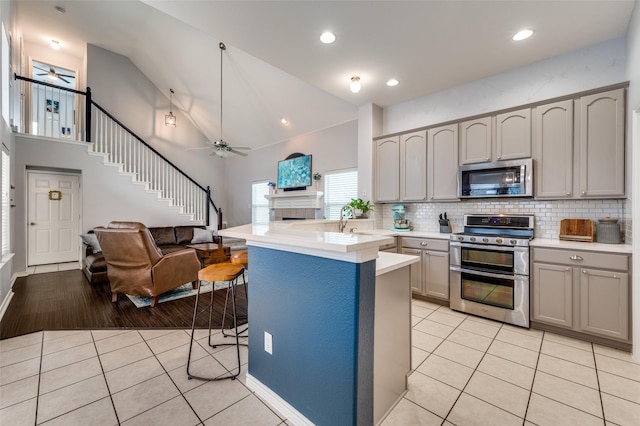 kitchen with light tile patterned floors, a ceiling fan, gray cabinetry, stainless steel appliances, and light countertops