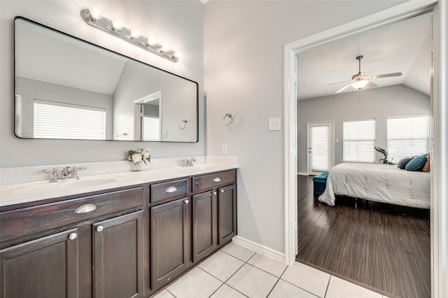 ensuite bathroom featuring tile patterned floors, connected bathroom, lofted ceiling, and a sink