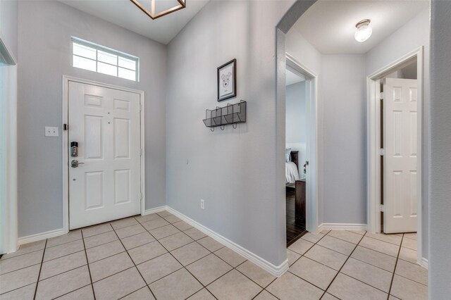 entryway with light tile patterned floors, baseboards, and arched walkways