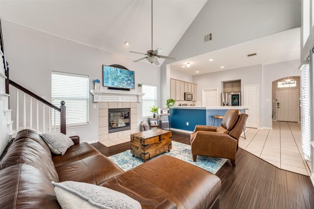 living room with visible vents, high vaulted ceiling, a fireplace, light wood finished floors, and stairs