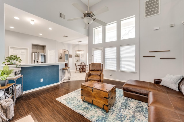 living area with ceiling fan, visible vents, baseboards, and dark wood finished floors