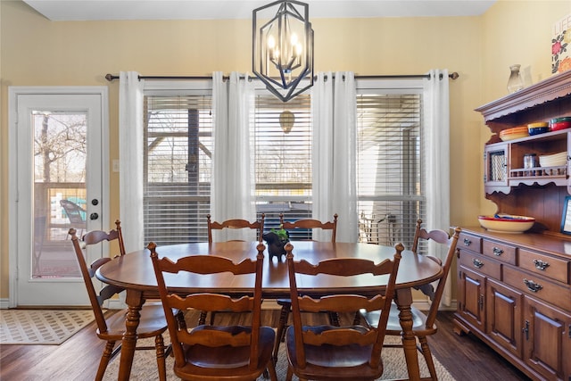 dining area with a chandelier, baseboards, and dark wood-style flooring