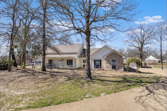 view of front of home featuring a porch, stone siding, and a front yard