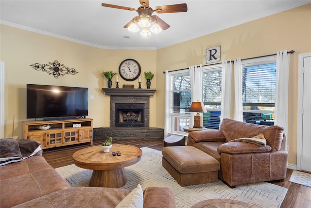 living room with a ceiling fan, wood finished floors, a fireplace, and ornamental molding