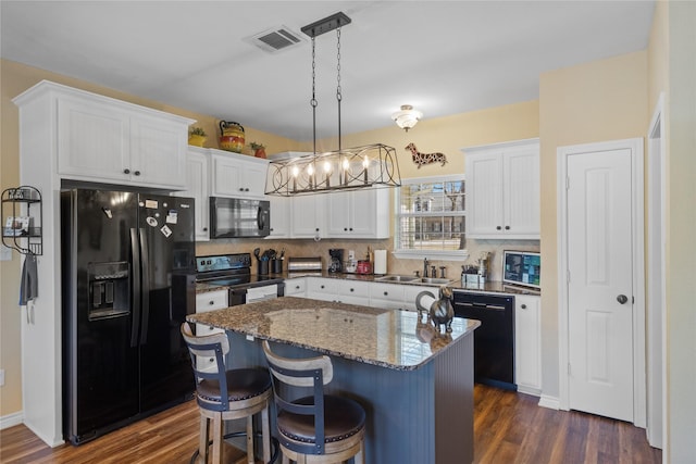 kitchen with backsplash, white cabinets, black appliances, and a sink