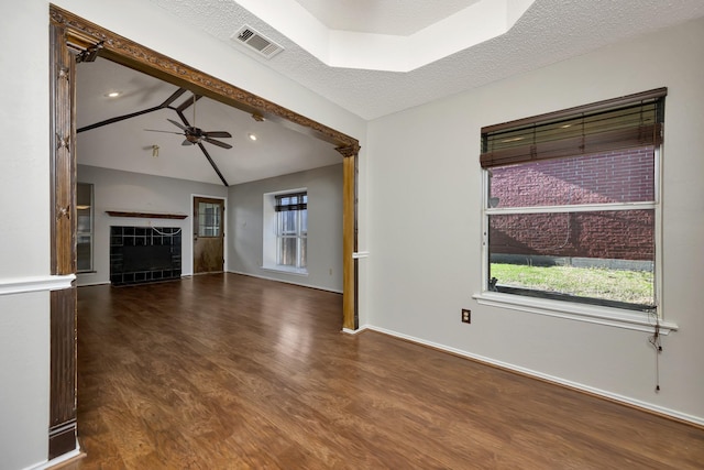 unfurnished living room featuring wood finished floors, visible vents, a ceiling fan, vaulted ceiling, and a tiled fireplace