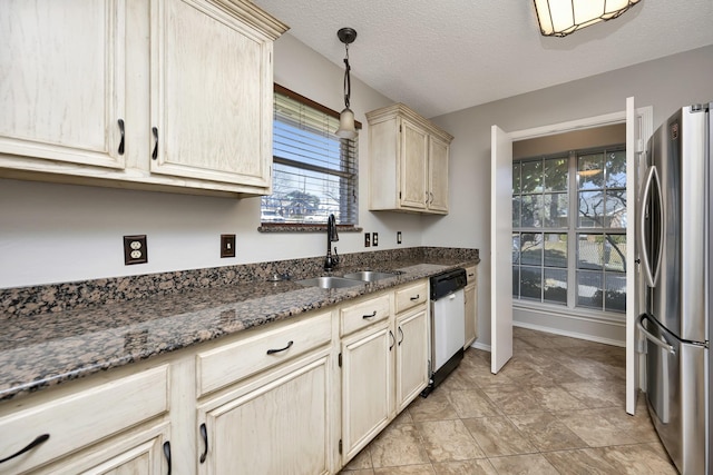 kitchen featuring dark stone counters, white dishwasher, freestanding refrigerator, a sink, and a textured ceiling