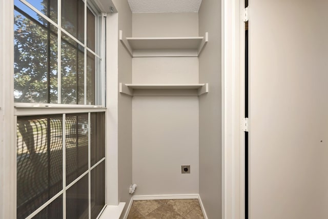 laundry area featuring laundry area, electric dryer hookup, a textured ceiling, and baseboards