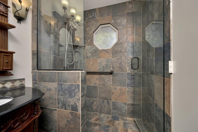 full bathroom with a tile shower, a textured ceiling, and vanity