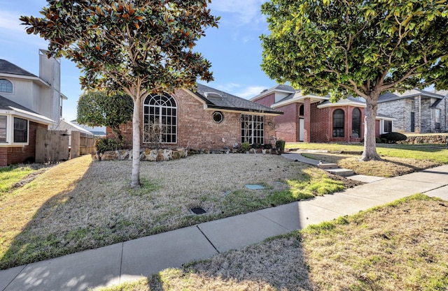 view of front of house featuring a front lawn, fence, and brick siding