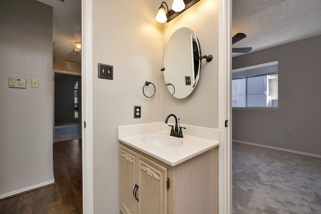 bathroom featuring vanity, wood finished floors, baseboards, and a textured ceiling